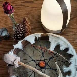 A reading lamp next to a Shaman drum with a red rose at the side. Art Sound Medicine Woman is setting all up for a ritual.