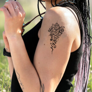 Woman with light brown skin showing left shoulder with medium sized Soul Tattoo on it.